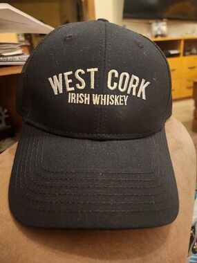 Black baseball caps featuring the embroidered logo for West Cork Irish Whiskey